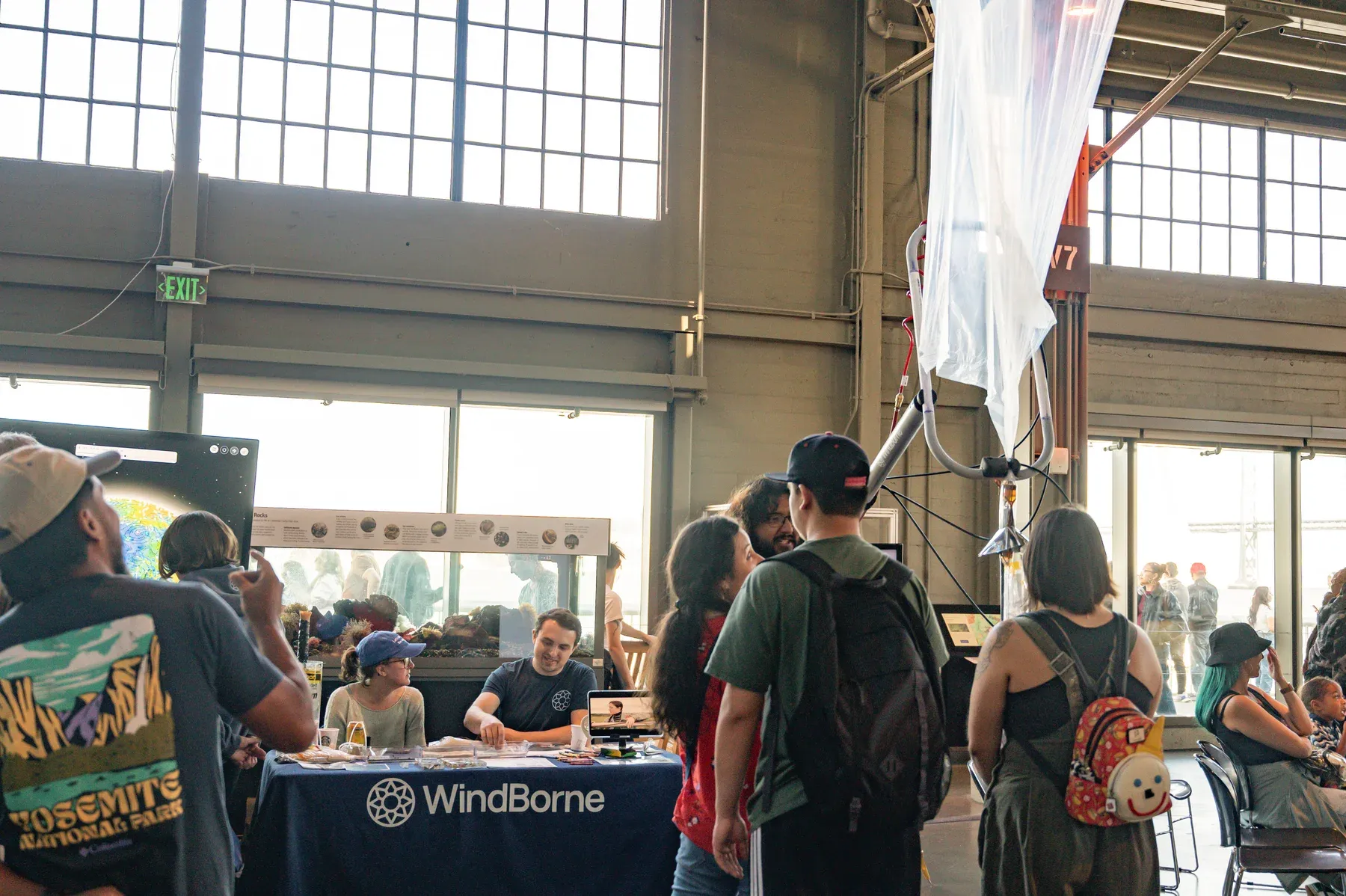 WindBorne team members talking with visitors at a table beneath a suspended balloon