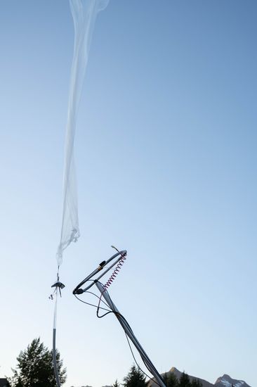 The balloon climbing away from the launch rig, its line trailing below.