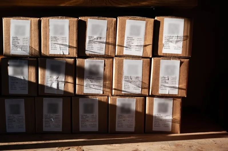 Stacked cardboard boxes of balloon envelopes, each with a tracking label.